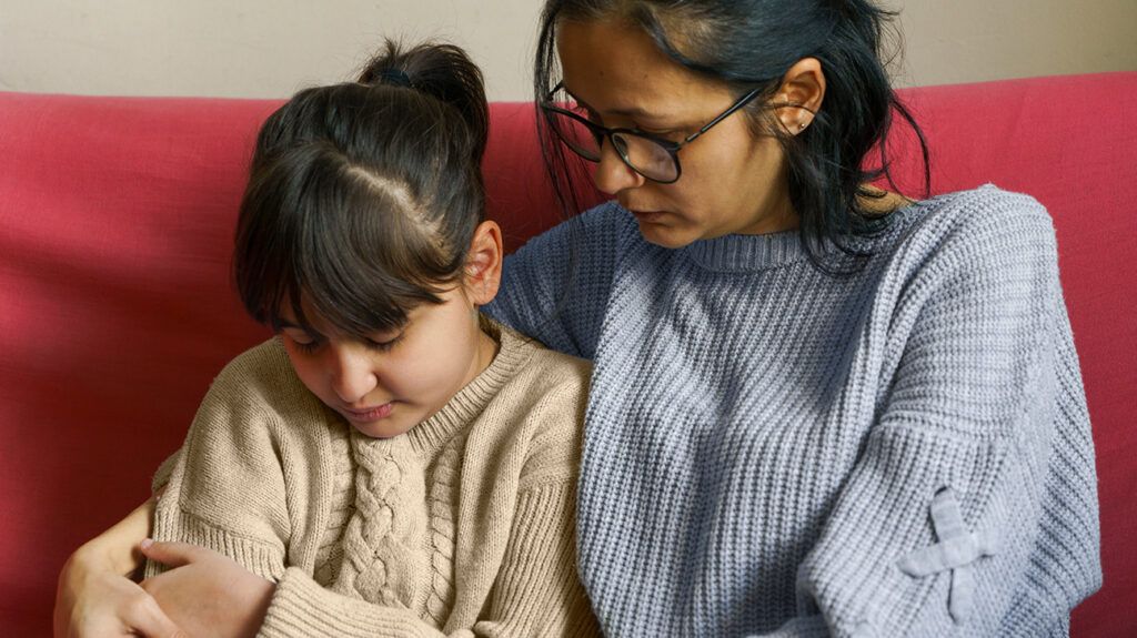 Mother embracing and listening to remorseful daughter who just lied to her